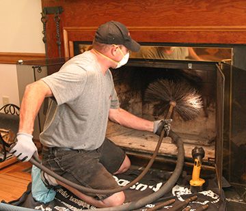 Technician vacuuming a firebox during a fireplace cleaning